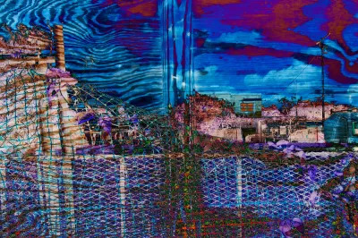 A composite photograph that has its colorization reversed showing a wired fence that is peeled back to show a neighborhood block.