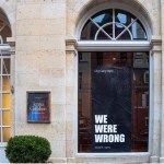 A gallery window that has a large black message pasted to it reading 