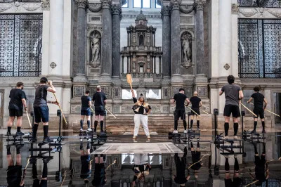 A person holding a paddle before rows of others with paddles with their backs turned. The stand before an altar in a church.