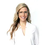 A smiling blonde white woman wearing glasses and a white shirt smiling.