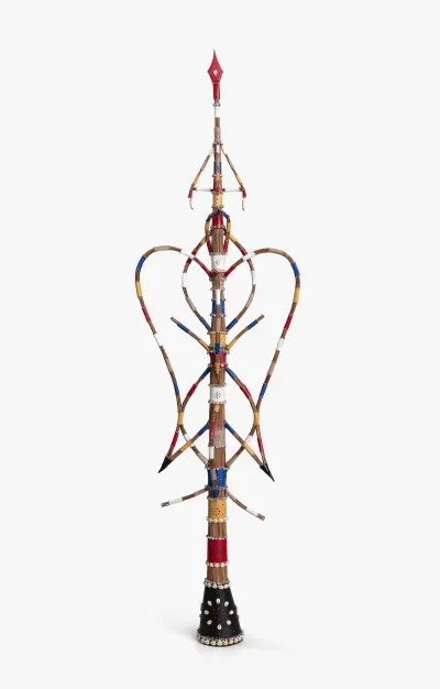 A sculpture resembling a multicolored staff with various hanging elements.
