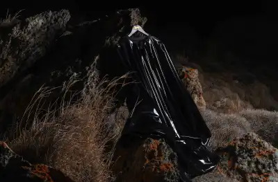 A hanger holding a black, rubbery garment. The hanger is hung from a rock.