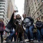 People pose next to a bronze sculpture.