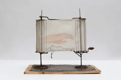 A sculpture resembling a scroll with a hand painted onto its translucent paper.