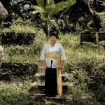 Portrait of Citra Sasmita standing outside in a lush area.