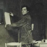 A man pinning a piece of paper to a wall and smiling.