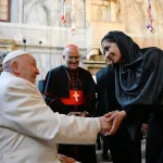 A man in papal robes greeting a woman in a black headscarf.