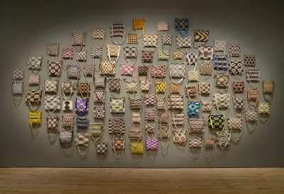 A group of 100 bags hung to a wall.