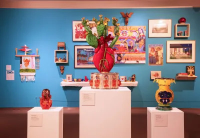 View of a museum exhibition with three sculptures on separate plinths in the front. 