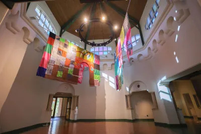 View of a museum exhibition with tapestries hanging from above.