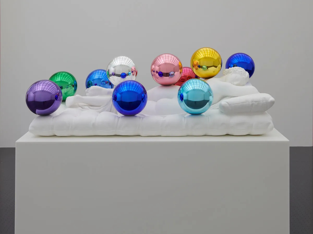 A marble sculpture of a sleeping figure covered with colorful highly polished orbs.