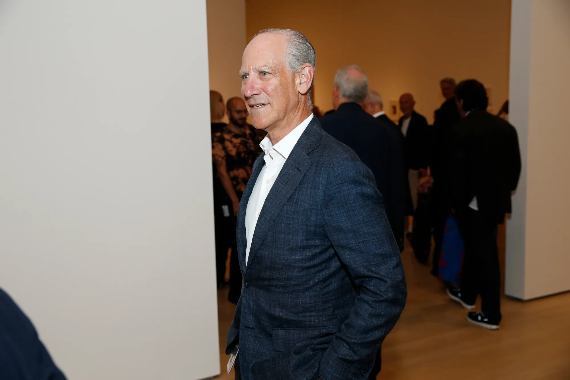 A man in a suit in a gallery.