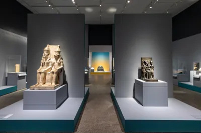 A gallery with two sculptures of seated pharaohs and gods.