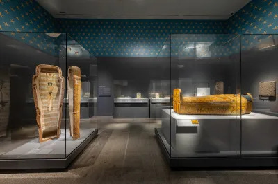 An open sarcophagus and a closed sarcophagus in a gallery with stars painted around the upper parts of its walls.