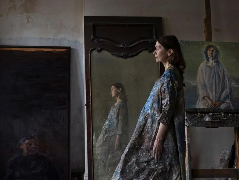 A photograph of a woman wearing a dress and standing in front of a mirror.