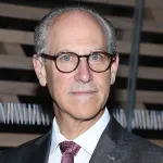 A white man in glasses smiling.