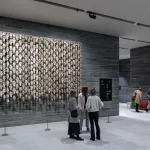 Installation view of a museum lobby showing people standing in front of an installation composed of reindeer skulls.