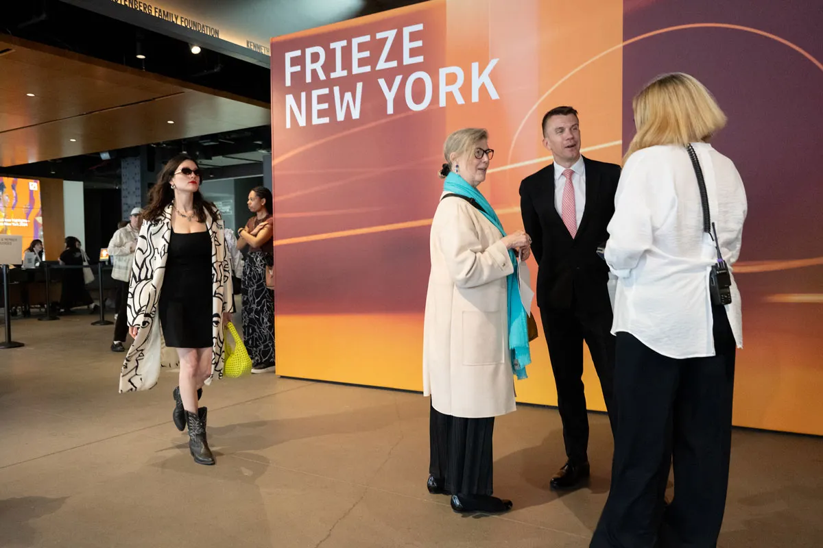 People stand in front of a sign that reads Frieze New York.